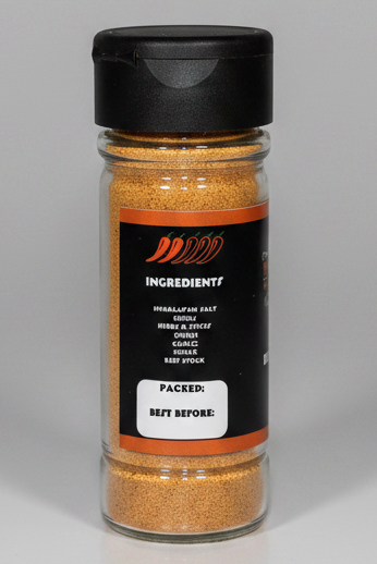 A clear plastic spice jar filled with a light brown seasoning blend, featuring a black lid and a black label with orange accents and white text.