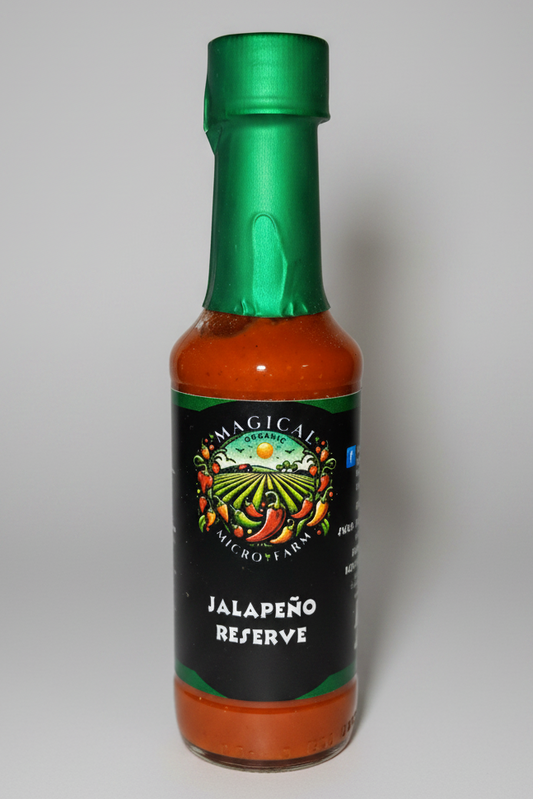 A bottle of Micro Farms Jalapeño Reserve hot sauce with a green cap and a black label featuring a colorful farm illustration.